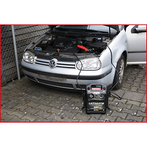 Ein silberner VW Golf mit geöffneter Motorhaube, Starthilfegerät angeschlossen. Darunter, ein schwarzes Ultimate-Gerät.